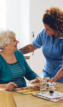 caregiver serving food to a senior woman