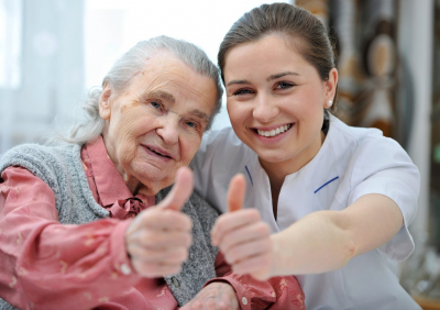 senior woman and her caregiver giving thumbs up